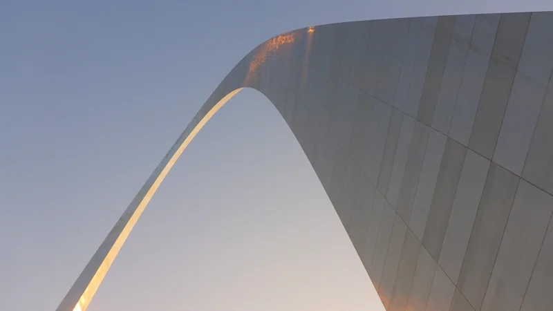looking up at the curve of the Gateway Arch against the sky
